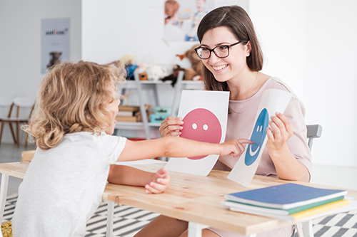 Smiling counselor holding pictures during meeting with young patient